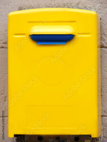 Yellow public mailbox on the wall on the wall of a building © zenobillis