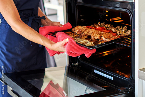 Photos Beautiful young woman preparing meat in oven in the domestic kitchen