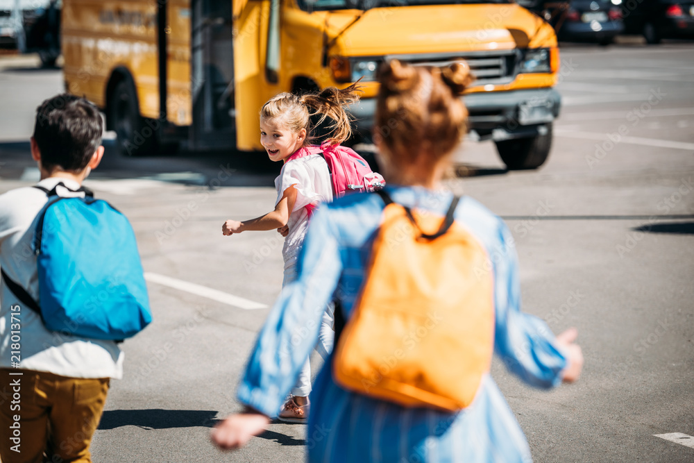 rear view of happy schoolchildren running to school bus