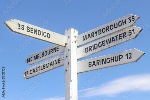 painted wooden signpost at Maldon town centre showing distance and directions to surrounding towns and a blue sky