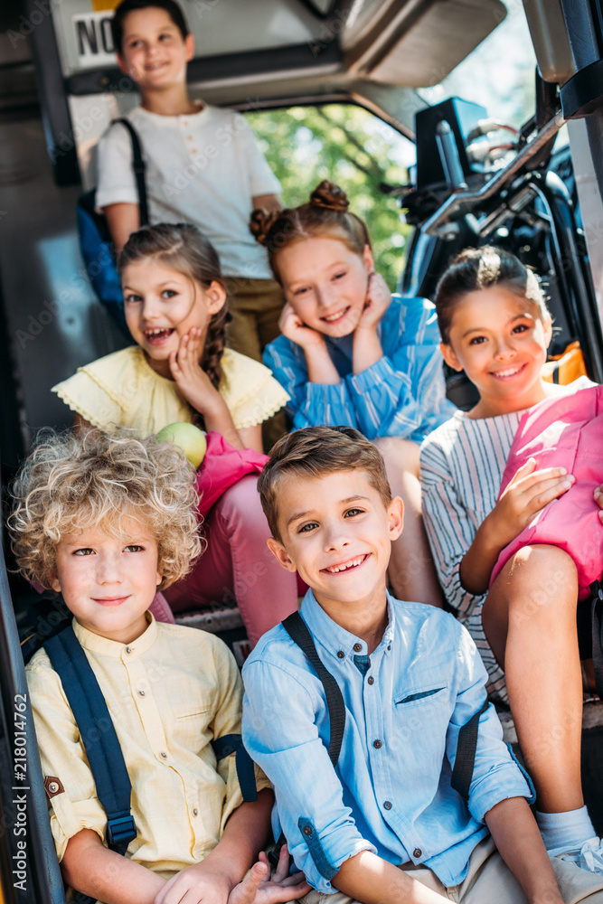 group of adorable pupils sitting on stairs of school bus and looking at camera group of adorable pupils sitting on stairs of school bus and looking at camera