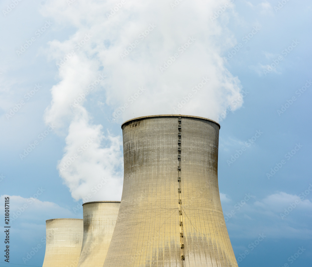 Three natural draft cooling towers of a nuclear power plant releasing clouds of water vapor against a dark stormy sky. Three natural draft cooling towers of a nuclear power plant releasing clouds of water vapor against a dark stormy sky.
