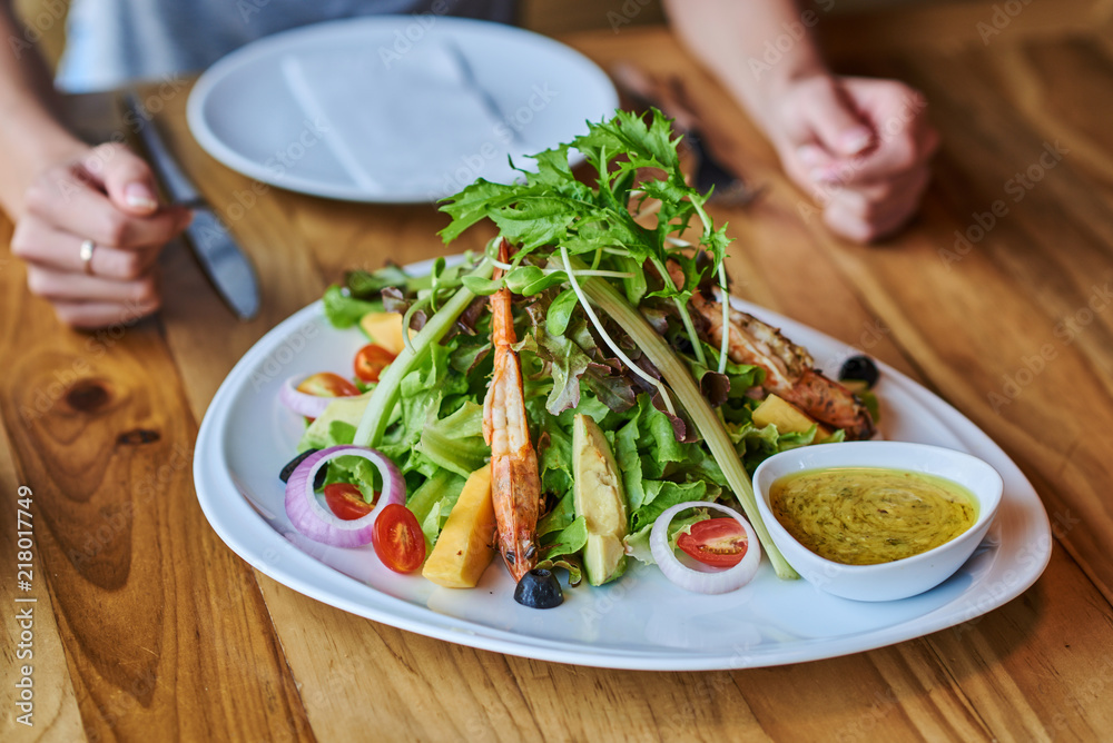 Healthy prawn and arugula salad with tomatoes on a wooden table. Healthy prawn and arugula salad with tomatoes on a wooden table.