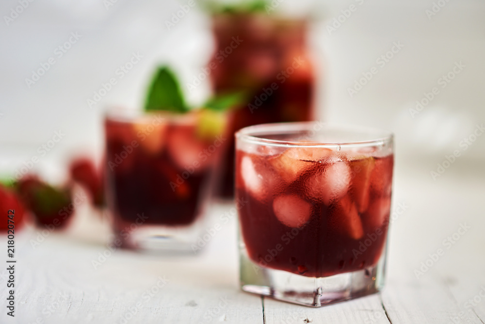 Refreshing sangria or punch with fruits in glasses and pitcher. Traditional summer drink beverage. Red wine, strawberries, oranges, lemon, and green apple. On a wooden rustic table with copy space.. Refreshing sangria or punch with fruits in glasses and pitcher. Traditional summer drink beverage. Red wine, strawberries, oranges, lemon, and green apple. On a wooden rustic table with copy space..