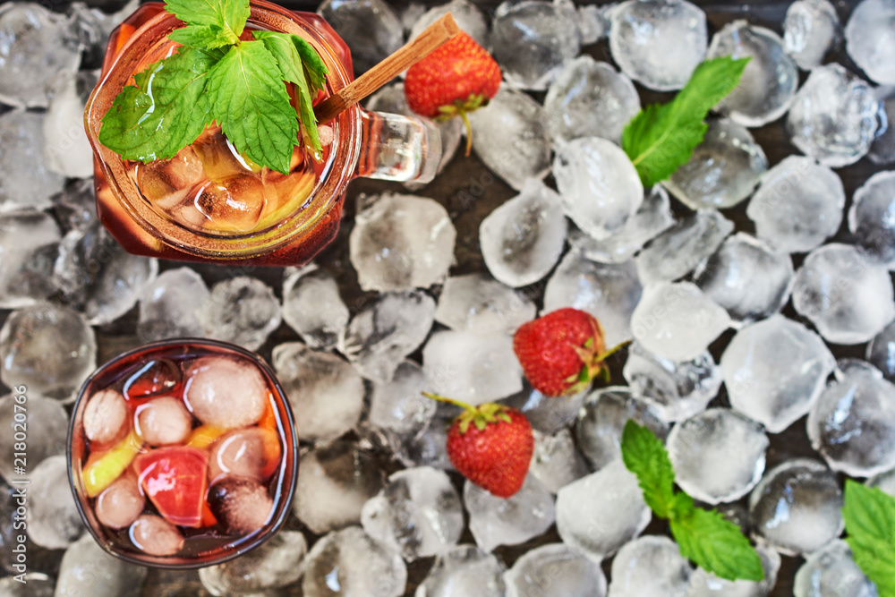 A carafe and glass of sangria, a typical Spanish alcoholic drink. Red sangria with fruit and ice. Traditional summer refreshing drink, cocktail. Top view on the ice cubes background with copy space. A carafe and glass of sangria, a typical Spanish alcoholic drink. Red sangria with fruit and ice. Traditional summer refreshing drink, cocktail. Top view on the ice cubes background with copy space.