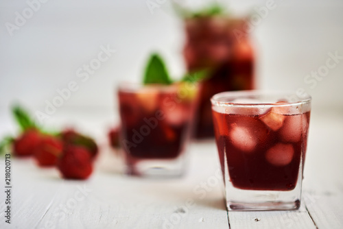 Refreshing sangria or punch with fruits in glasses and pitcher.  Traditional summer drink beverage. Red wine, strawberries, oranges, lemon, and green apple. On a wooden rustic table with copy space..