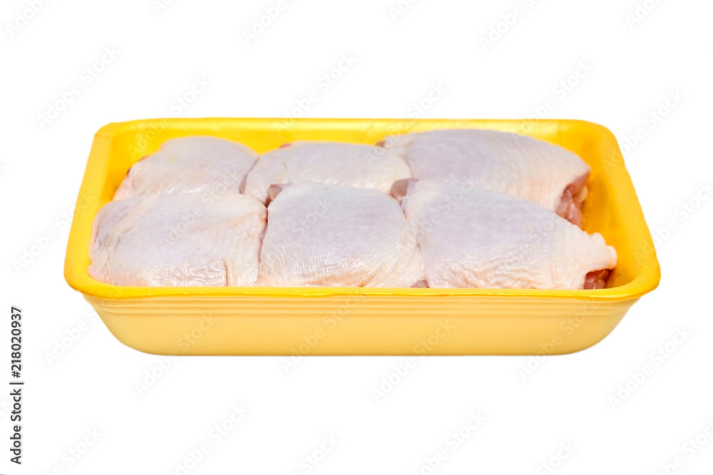 Raw and uncooked chicken thighs in a yellow plastic container. Meat of poultry in tray, isolated on white background Raw and uncooked chicken thighs in a yellow plastic container. Meat of poultry in tray, isolated on white background