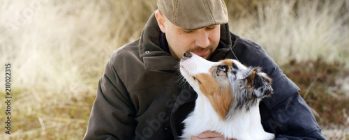 Mensch und Hund, outdoor in herbstlicher Landschaft schauen sich voller Vertrauen und Liebe in die Augen.