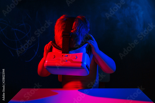 infant baby uses virtual reality VR cardboard isolated on black background. Red blue double color lighting