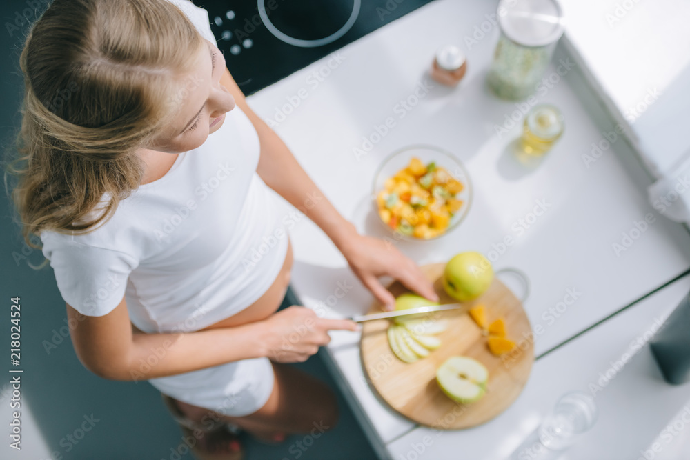 overhead view of pregnant woman with knife cooking fruits salad at home overhead view of pregnant woman with knife cooking fruits salad at home