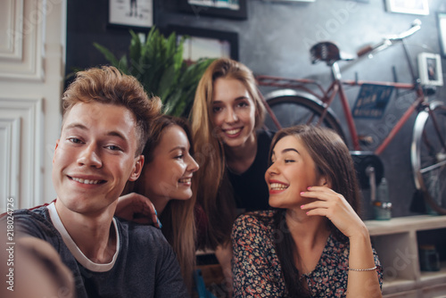 Fototapeta Group of cute teenagers taking selfie with cellphone while sitting in a restaura