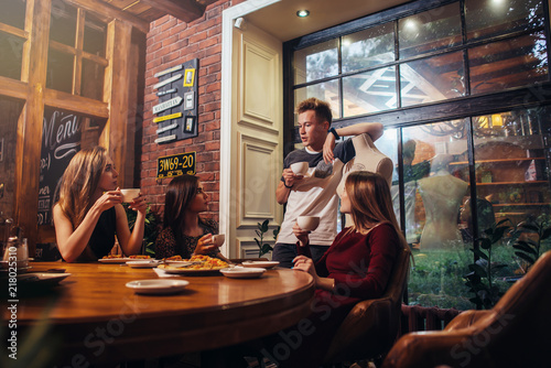 Fotografia Serious young people sitting in a fashionable cafe drinking tea discussing