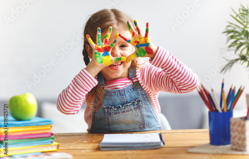 Fototapeta Naklejka Na Ścianę i Meble -  funny child girl draws laughing shows hands dirty with paint