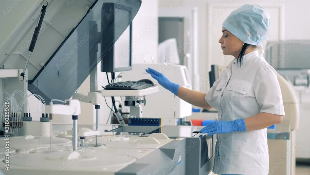 Female lab expert is managing Automatic Pharmaceutical Equipment. Female lab expert is managing Automatic Pharmaceutical Equipment.