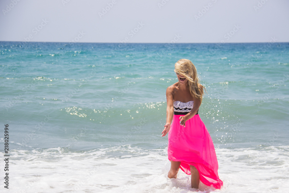Happy laughing young Caucasian woman enjoying day at the beach on summer vacation. Healthy living natural beauty multiracial girl smiling with hair in the wind, tanned skin having a good time. Happy laughing young Caucasian woman enjoying day at the beach on summer vacation. Healthy living natural beauty multiracial girl smiling with hair in the wind, tanned skin having a good time.