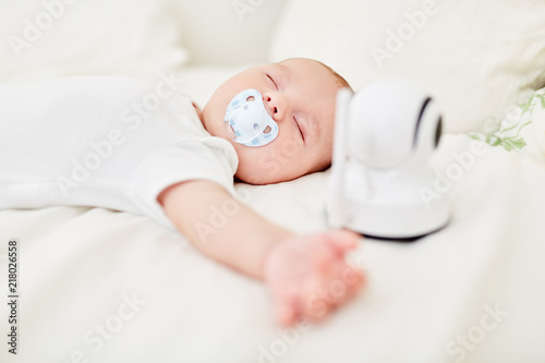 Baby schläft mit Babyphon am Babybett photo