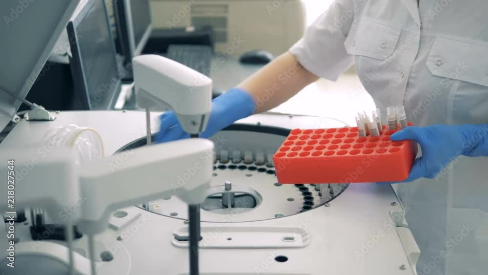Test tubes are getting inserted into a biochemical analyzer by a lab worker Test tubes are getting inserted into a biochemical analyzer by a lab worker