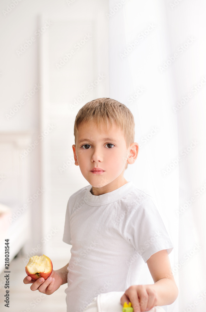 teenager holding an apple in his hand on a white wall teenager holding an apple in his hand on a white wall