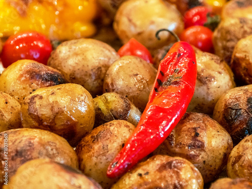 Roasted red pepper lies on the baked potat, close up. Grilled food. Festival of street food. Appetizing potatoes in oil. Fast food restaurant. Vegan food. photo