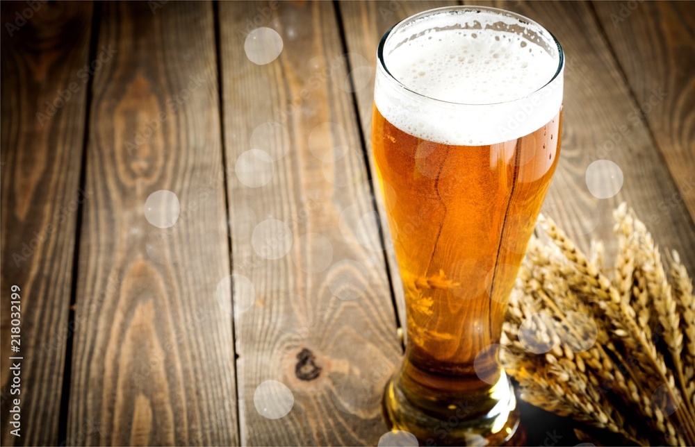 Glass of light beer on background