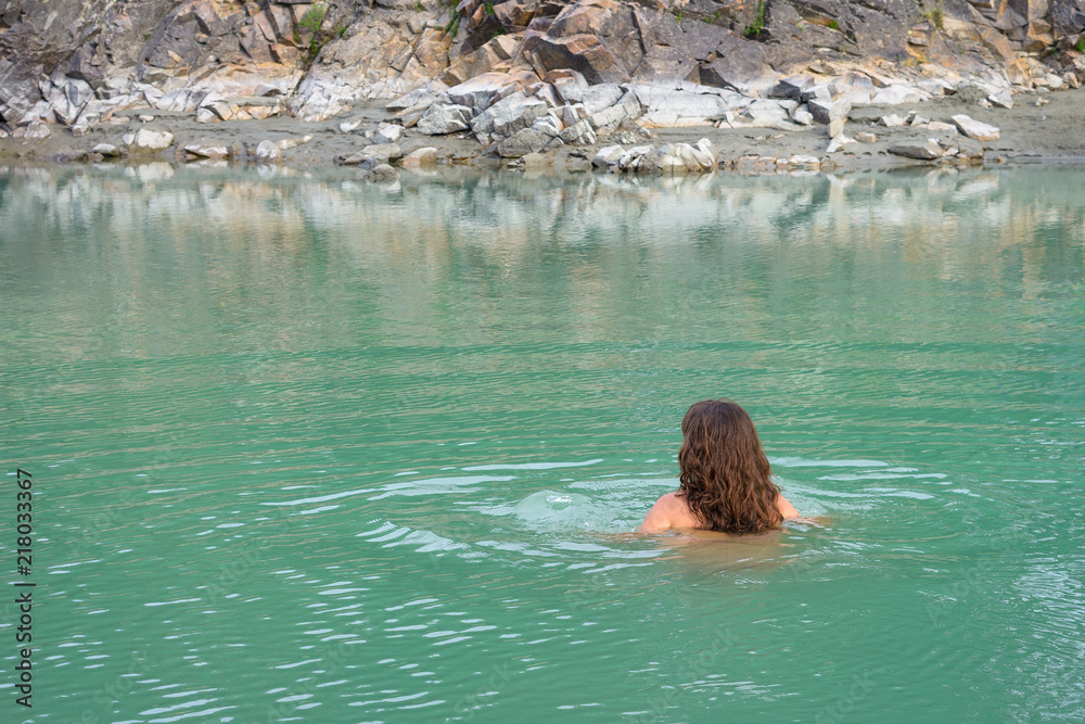 A young woman swim in a cool mountain lake