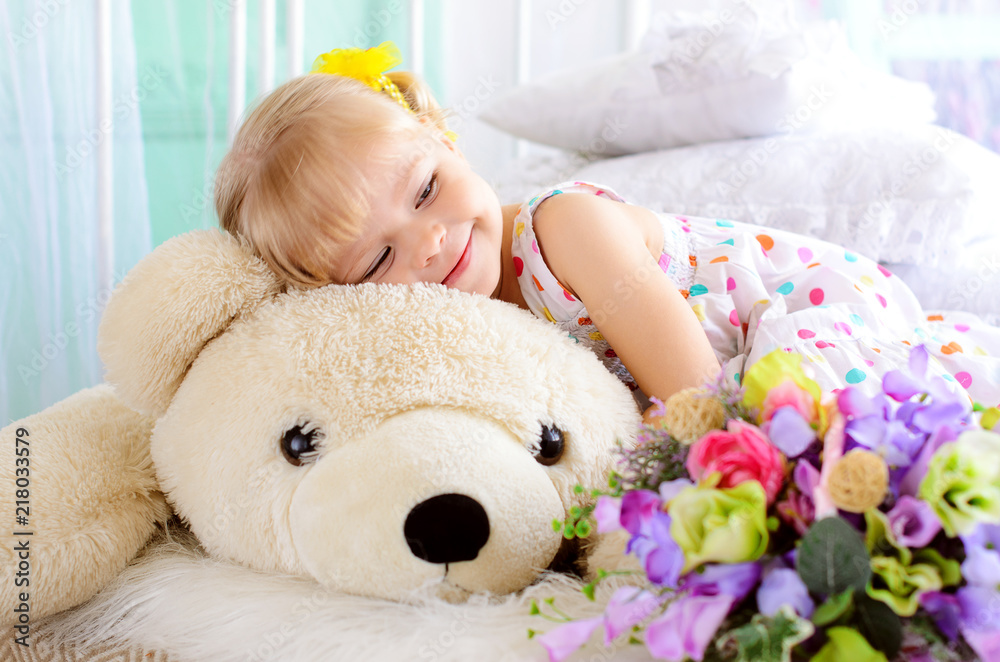 blonde girl embracing big white teddy bear