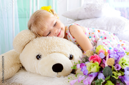 blonde girl embracing big white teddy bear