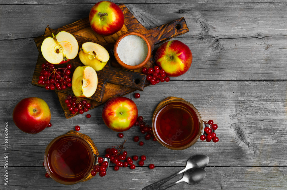 Autumn tea drink (compote) from apples and berries of Kalina. Ingredients are sugar, calyx berries, fresh sliced apples. Rustic gray vintage background. Top view Autumn tea drink (compote) from apples and berries of Kalina. Ingredients are sugar, calyx berries, fresh sliced apples. Rustic gray vintage background. Top view