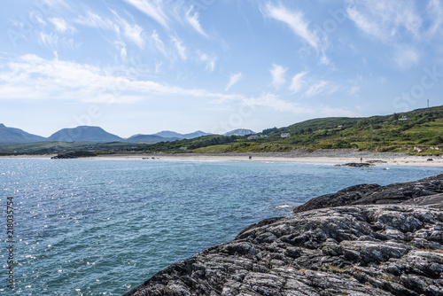 Renvyle beach, taken from the rocks, showing blue sky and surrounding mountains in summer. photo