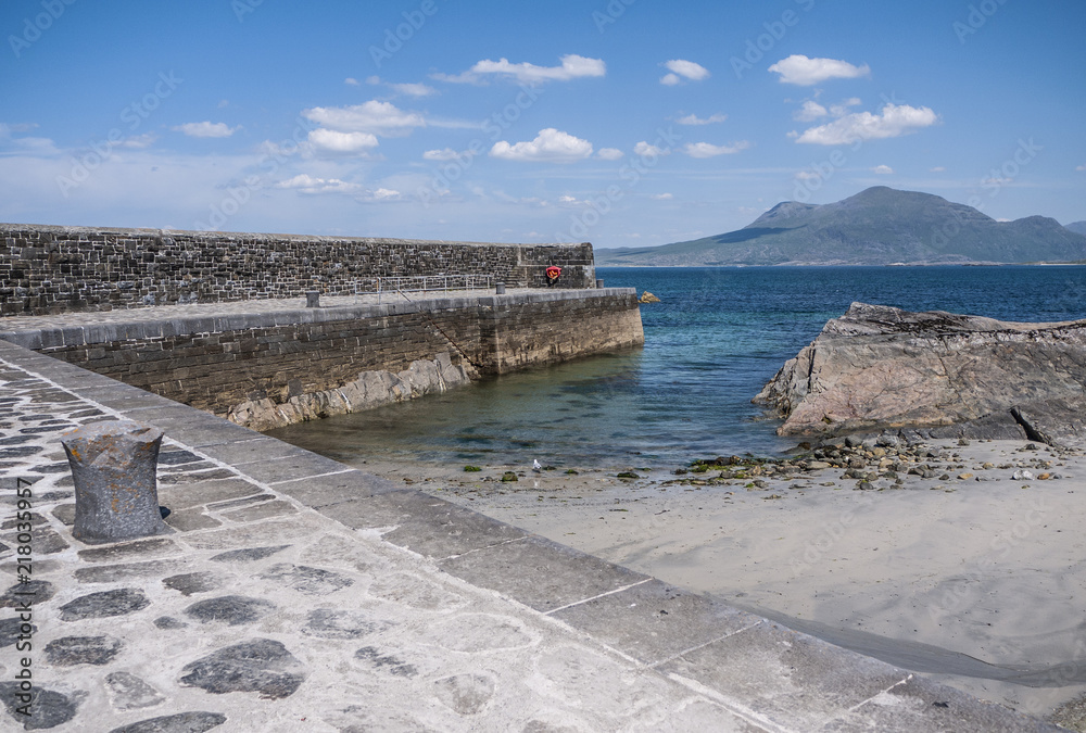 Old stone pier on a sunny summer day with mountains in the distance. Taken in Renvylle along the Wild Atlantic Way, Ireland.