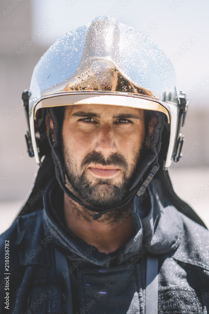 Firefighter poses with helmet looking at camera. Firefighter poses with helmet looking at camera.