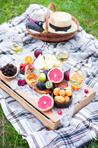 Picnic background with white wine and summer fruits on green grass, top view