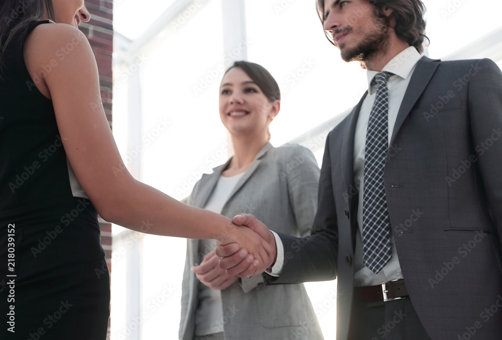 Businesspeople shaking hands against room with large window loo Businesspeople shaking hands against room with large window loo