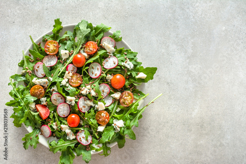 Fresh salad with arugula and vegetables - feta cheese, tomato, seeds and radish. Organic vegetable diet, vegetarian food concept.