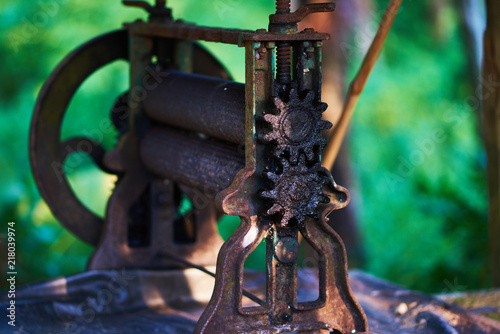 Abandoned palm oil press. Old iron press for pressing palm oil in green landscape.