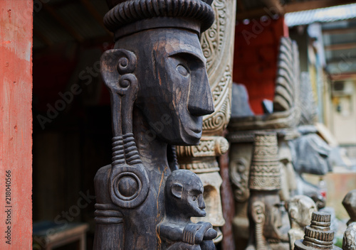 Group of different Balinese wooden statues displayed in art and craft tourist market. Indonesian handicrafts. Souvenir from Bali. Traditional wood carving. Сounter with balinese souvenirs..