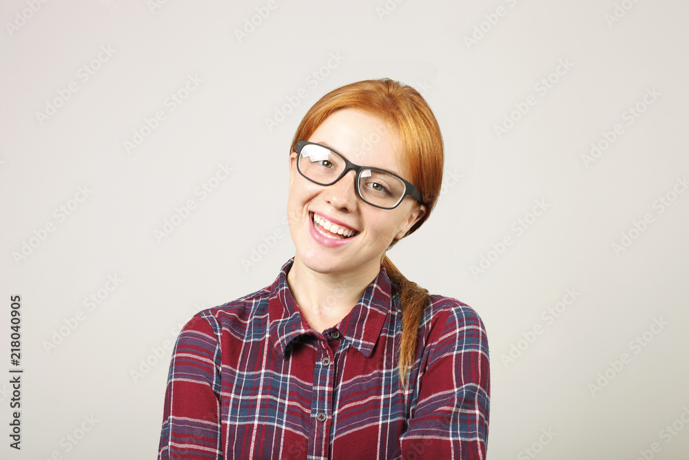 Close up portrait of beautiful young woman college student w/ red hair wearing black frame eye glasses & flannel shirt. Redhead female smiling. Redhead female in casual outfit. Background, copy space.