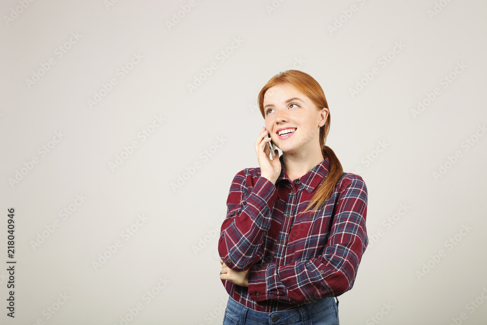 Portrait of young beautiful woman with long red hair wearing flannel shirt, talking on mobile phone. Smiling attractive female having smartphone conversation. Isolated background, copy space, close up Portrait of young beautiful woman with long red hair wearing flannel shirt, talking on mobile phone. Smiling attractive female having smartphone conversation. Isolated background, copy space, close up