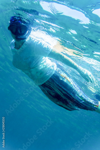 A woman is engaged in snorkeling in the tropical sea in ordinary clothes, which protects from sunburn and scratches 