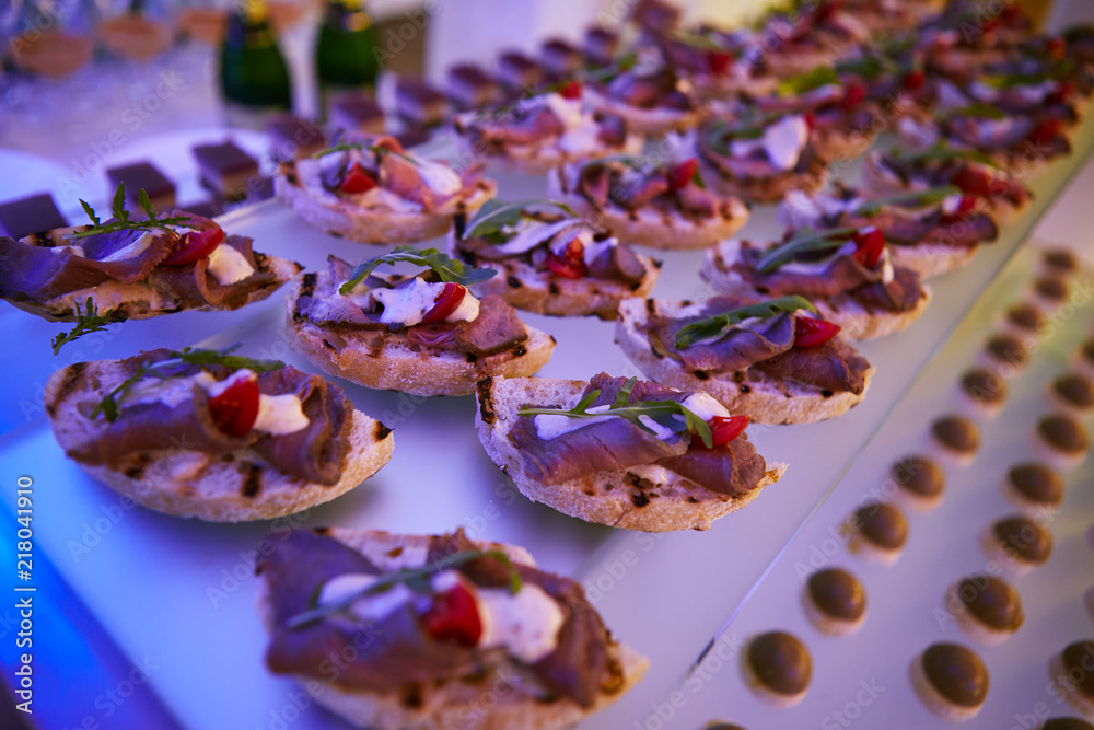Beautifully decorated catering banquet table with different food snacks and appetizers on corporate christmas birthday party event or wedding celebration Beautifully decorated catering banquet table with different food snacks and appetizers on corporate christmas birthday party event or wedding celebration