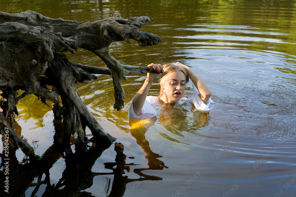 Fototapeta premium Beautiful girl in a white dress in the water.