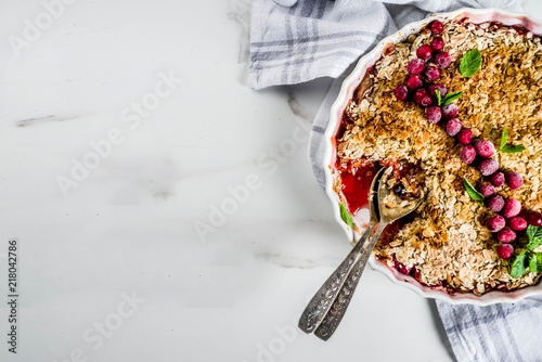 Traditional autumn winter pastries, homemade pie crumble with apples and cranberries, on a white marble table, copy space for text photo