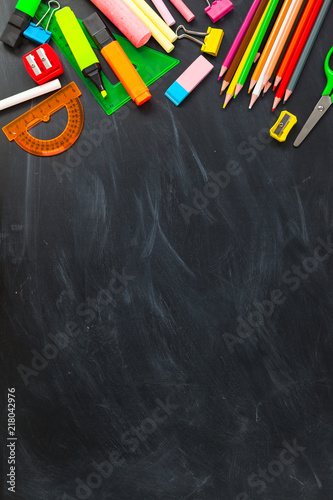 Back To School concept. School supplies on blackboard background, accessories for the schoolroom - pencils, notebooks, scissors, chalk, markers.