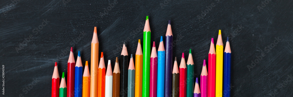 Back to School concept. Color pencils on blackboard background. Close up, flat lay, copy space, top view Back to School concept. Color pencils on blackboard background. Close up, flat lay, copy space, top view