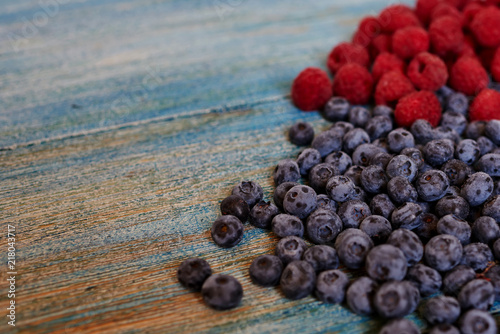 Berries on blue background. Summer or spring organic berry. Agriculture, gardening, harvest concept. Fresh sweet blueberry, raspberry fruit. Healthy food. Selective focus. Top view with copy space.