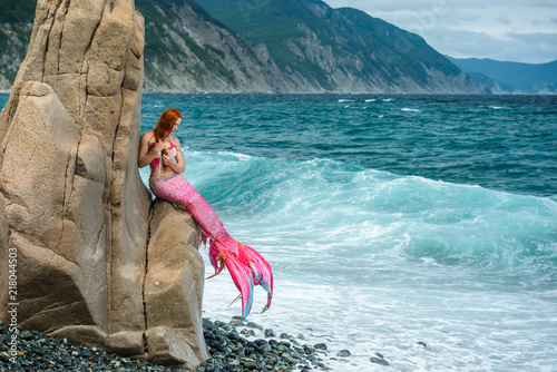 Beautiful mermaid with long tail on sea shore
