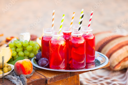 Picnic on the beach at sunset in the style of boho. Concept outdoors evening healthy dinnner with fruit and juice