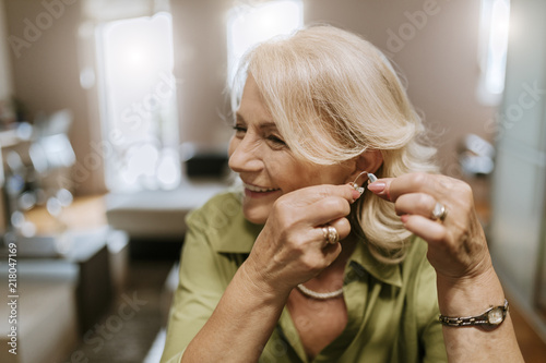 Senior woman applying hearing aid photo