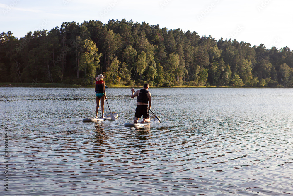 Stand up paddle boarding sup on a quiet lake with warm summer sunset colours