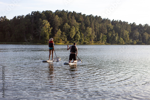 Stand up paddle boarding sup on a quiet lake with warm summer sunset colours